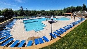 Ein Swimmingpool mit blauen Liegestühlen und einem Pavillon.