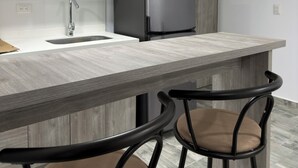 A modern kitchen with a built-in refrigerator, a sink, and two bar stools.