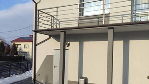 A two-story building with a balcony, a door, and a trash bin. - Kielce Urban Oasis Apartment (Kielce)