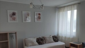 A living room with a sofa, a small table, a cabinet, and a ceiling light fixture. - Kielce Urban Oasis Apartment (Kielce)