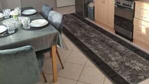 A compact kitchen with a dining area, featuring a microwave, kettle, and stove. - Kielce Urban Oasis Apartment (Kielce)