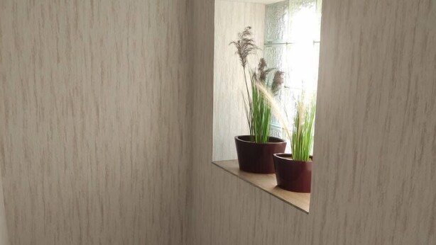 A modern interior with a wooden staircase, a small window with a view of greenery, and a mirror reflecting the window. - Kielce Urban Oasis Apartment (Kielce)