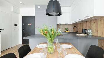 A modern kitchen with white cabinets, a wooden countertop, and a black pendant light.