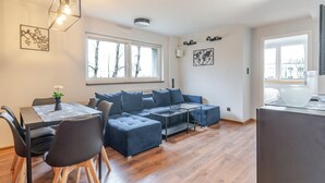 Una sala moderna con un sofá, una mesa de comedor y una zona de cocina.