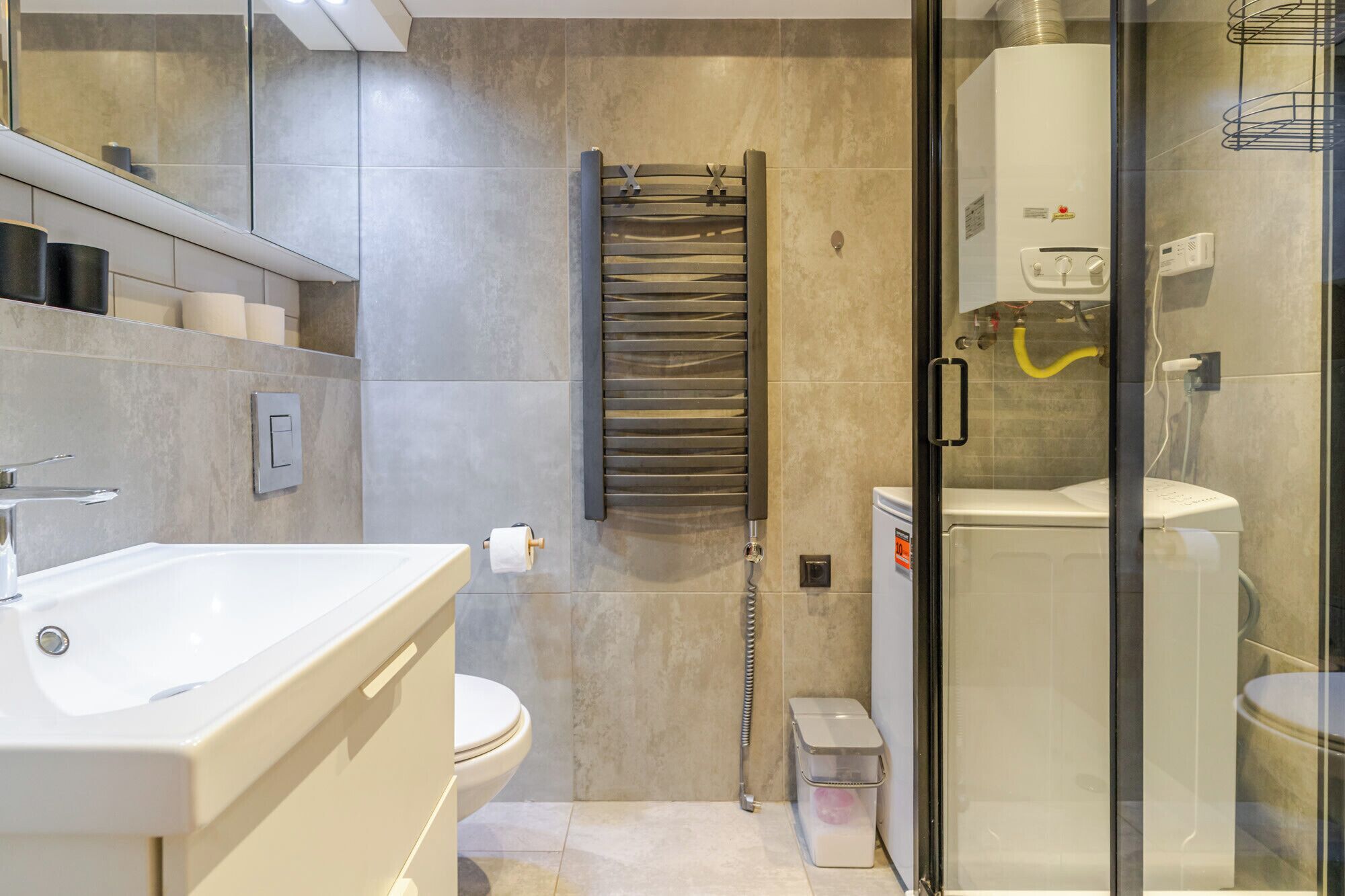 A modern bathroom with a glass shower enclosure, a white toilet, and a built-in towel rack.