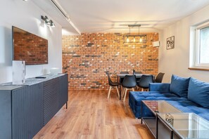 Un salon moderne avec un mur en briques, un canapé, une table basse et un coin repas comprenant des chaises et une table.