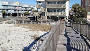 A beachfront hotel with a wooden boardwalk leading to the entrance. - Property is a great spot to relax in the sun with beach front and ocean view. (Gulf Shores)