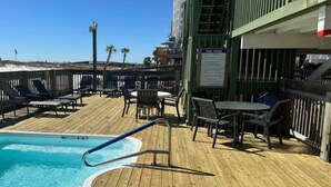 A pool area with a wooden deck, lounge chairs, and a sign indicating pool rules. - Property is a great spot to relax in the sun with beach front and ocean view. (Gulf Shores)