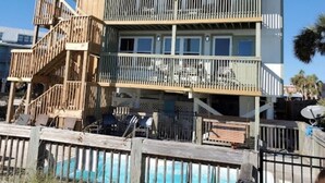 A multi-story beachfront house with a wooden deck, a pool, and a balcony. - Property is a great spot to relax in the sun with beach front and ocean view. (Gulf Shores)