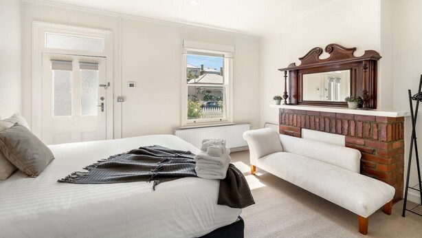 Une chambre à coucher avec un lit, un banc, une cheminée et un grand miroir.