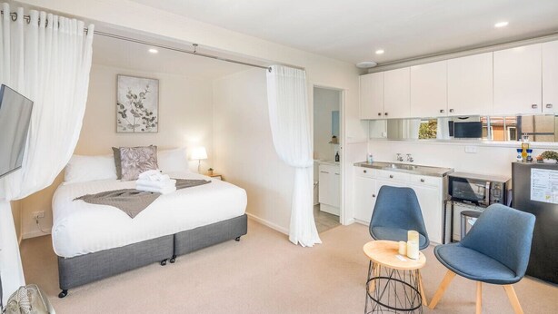 A modern hotel room with a bed, a desk, and a kitchenette. - Private North Hobart Cottage (North Hobart)