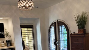 A bedroom with a large bed, a desk with a coffee maker, a dresser, and a chandelier. - Quiet 1-bedroom studio with AC in La Quinta.Walk to CoachellaFest/Stagecoach. (La Quinta)