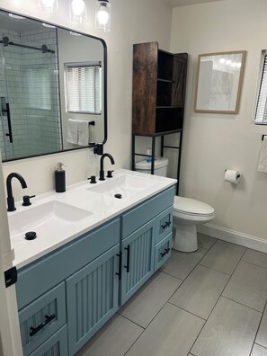 A bathroom with a double sink, a toilet, a mirror, and a framed picture on the wall. - The Victorian Row: private patio, 17 min to NYC (Newark)