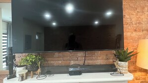 Un televisor de pantalla plana montado en una pared de ladrillo, sobre una repisa blanca con una chimenea debajo.