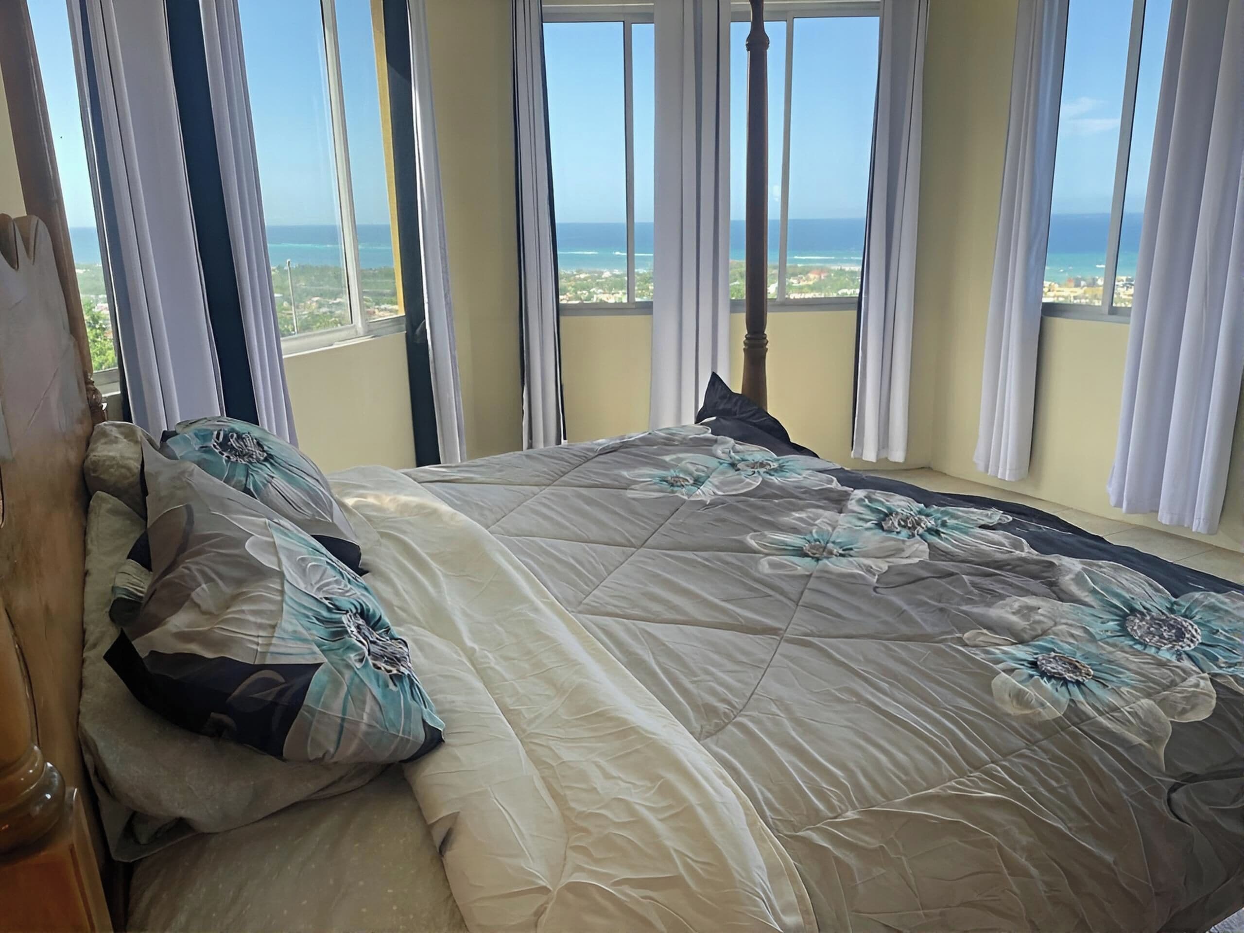 Un dormitorio con una cama grande, varias ventanas y vista al océano.