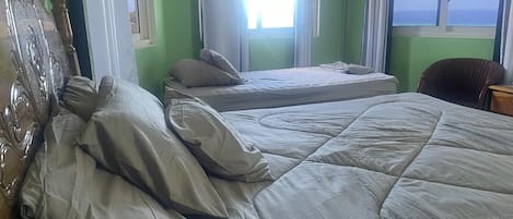 Una habitación con dos camas, una silla y una ventana con vistas.
