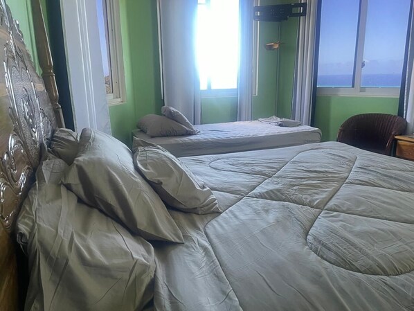 Een kamer met twee bedden, een stoel en een raam met uitzicht.