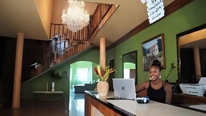 Un comptoir d’accueil avec un ordinateur portable, un vase de fleurs et un escalier en arrière-plan.