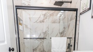 Un bagno moderno con doccia vetro, un water e un mobile lavabo con pensili.