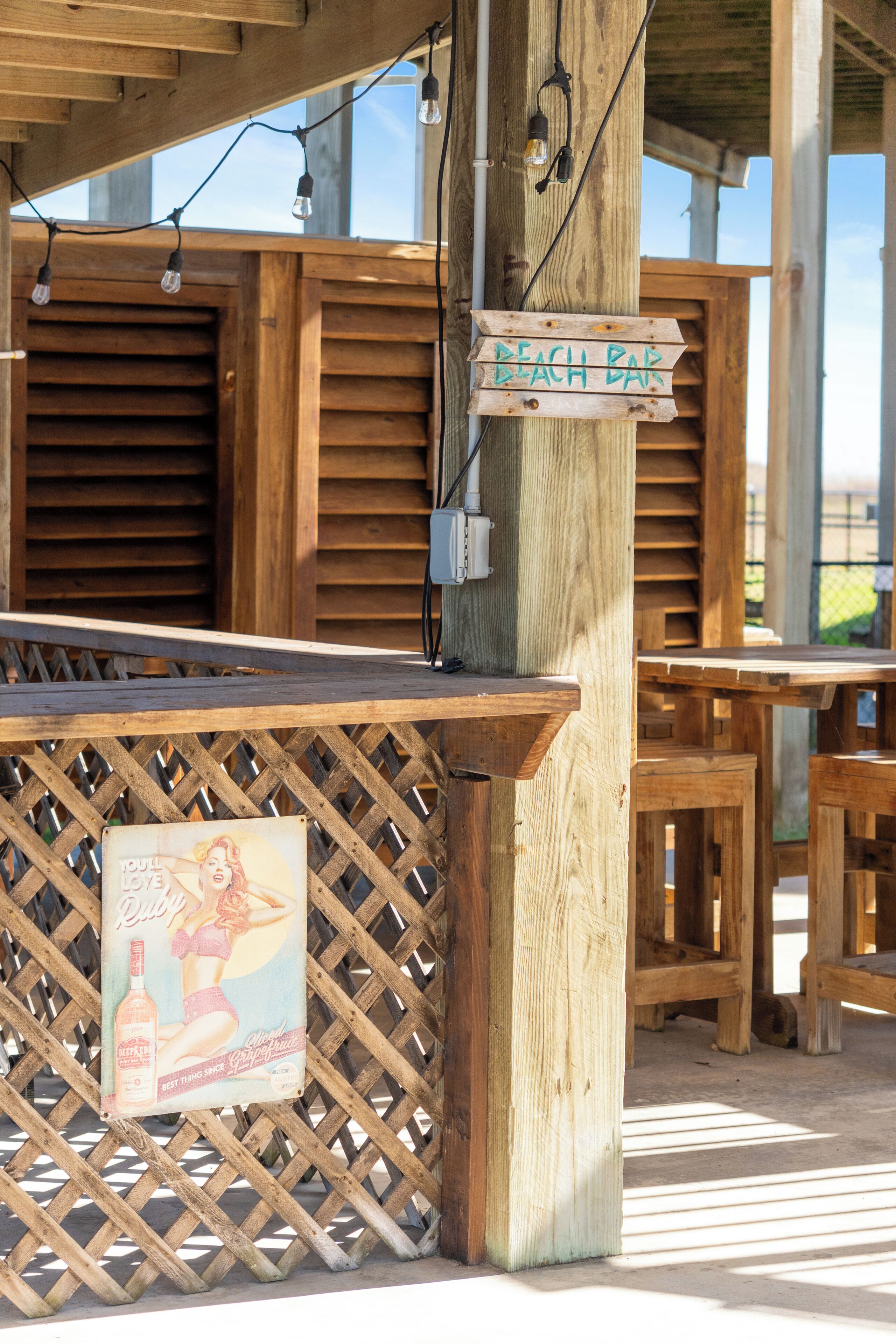 A wooden outdoor seating area with a sign reading "Beach Bar".