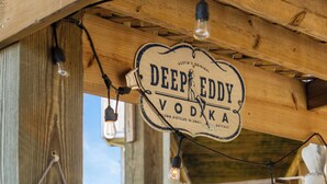 Une structure en bois sur laquelle est affiché un panneau indiquant « DEEP EDDY VODKA », et des tongs sont accrochées au mur.