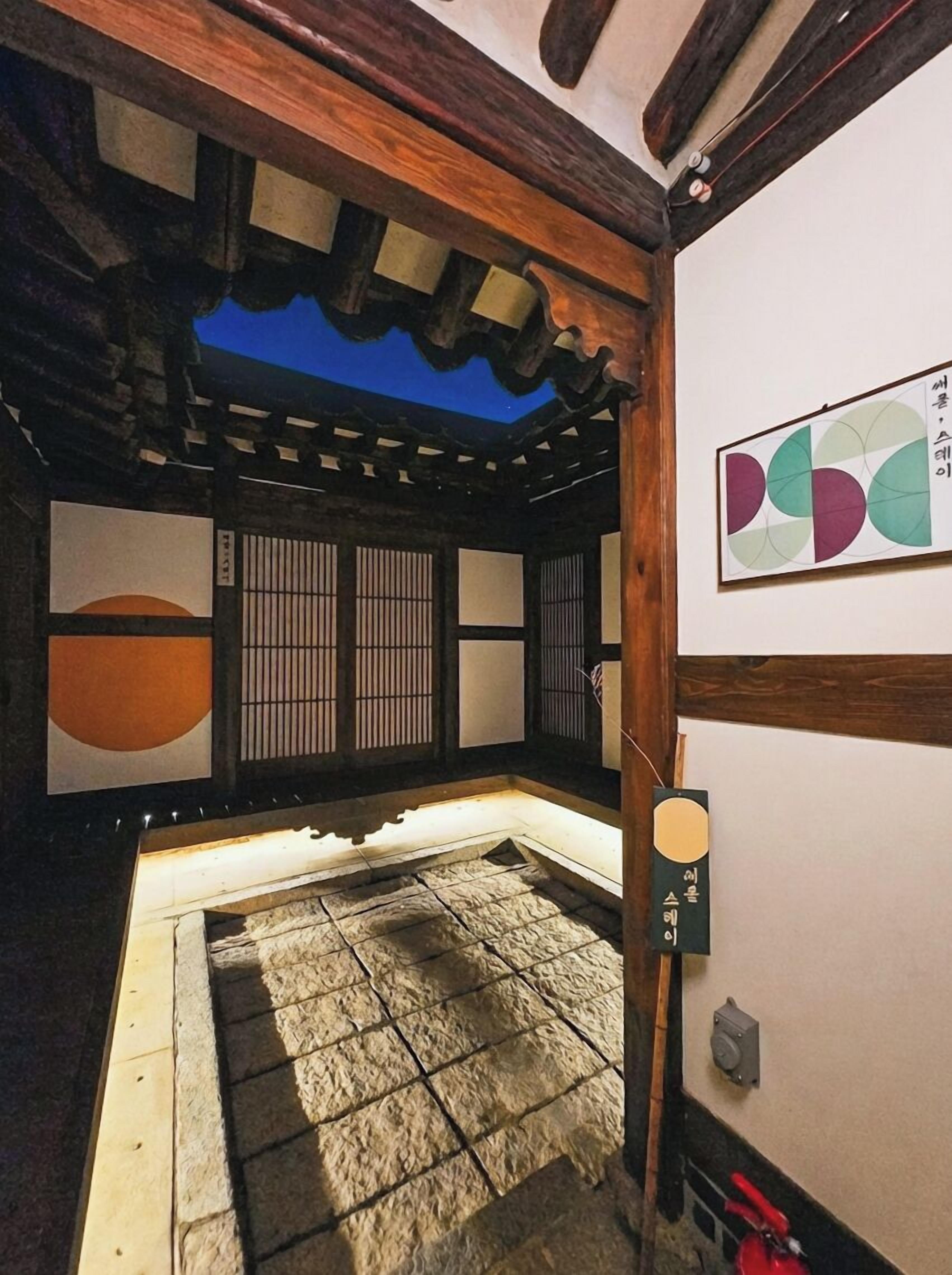 A traditional Japanese room with tatami flooring, shoji screens, and a wooden ceiling.