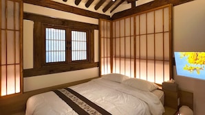 A traditional Japanese-style room with tatami flooring, a low bed with a decorative headboard, a shoji screen, and a mounted television. - Seoul Hanok Stay Circle (Seoul)