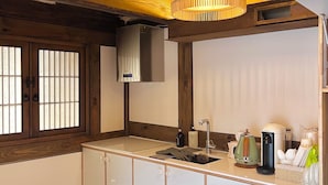 A kitchen with wooden beams, a hanging light fixture, a built-in sink, and various appliances. - Seoul Hanok Stay Circle (Seoul)