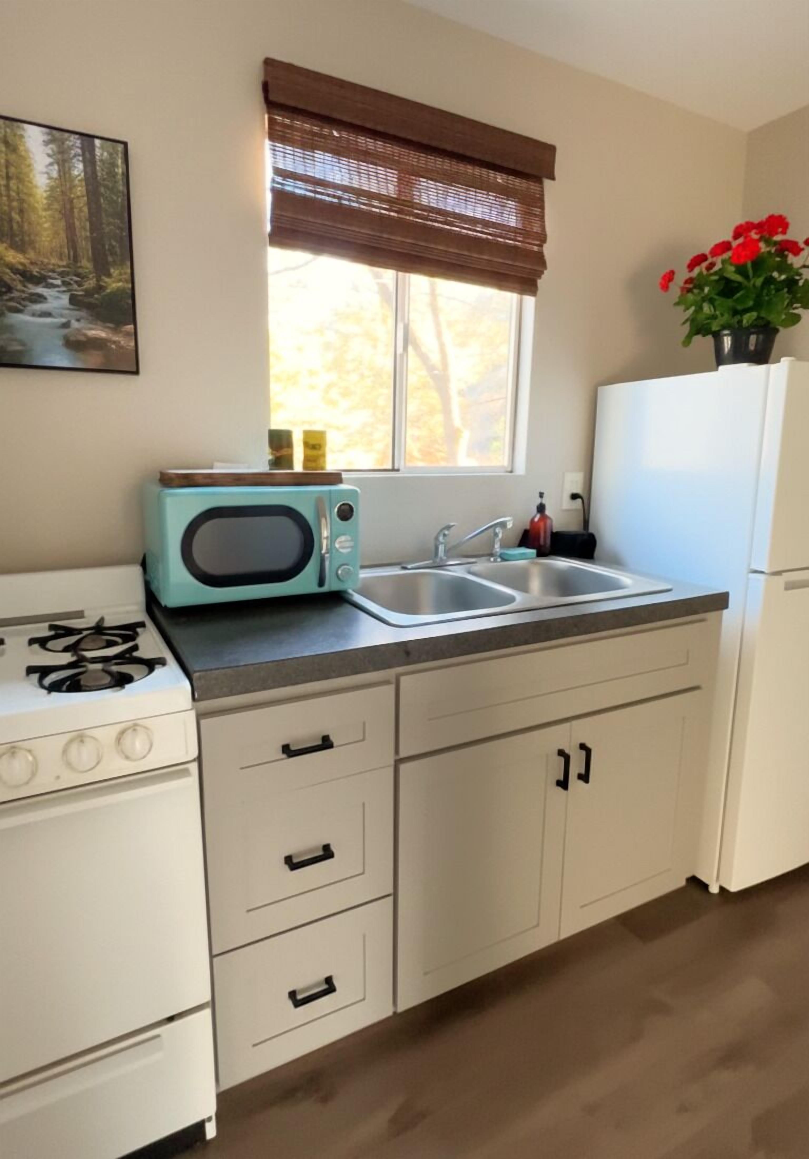 A kitchen with a stove, microwave, sink, and cabinets.