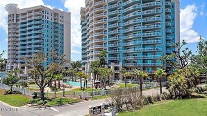A high-rise hotel with multiple balconies, a pool area, and a well-maintained lawn. - Amazing Gulf Views! Legacy Towers 10th Floor! (Gulfport)
