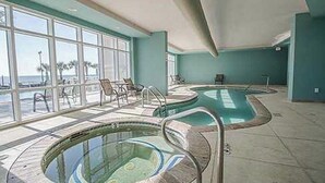 A pool area with two hot tubs and a seating area with chairs. - Amazing Gulf Views! Legacy Towers 10th Floor! (Gulfport)