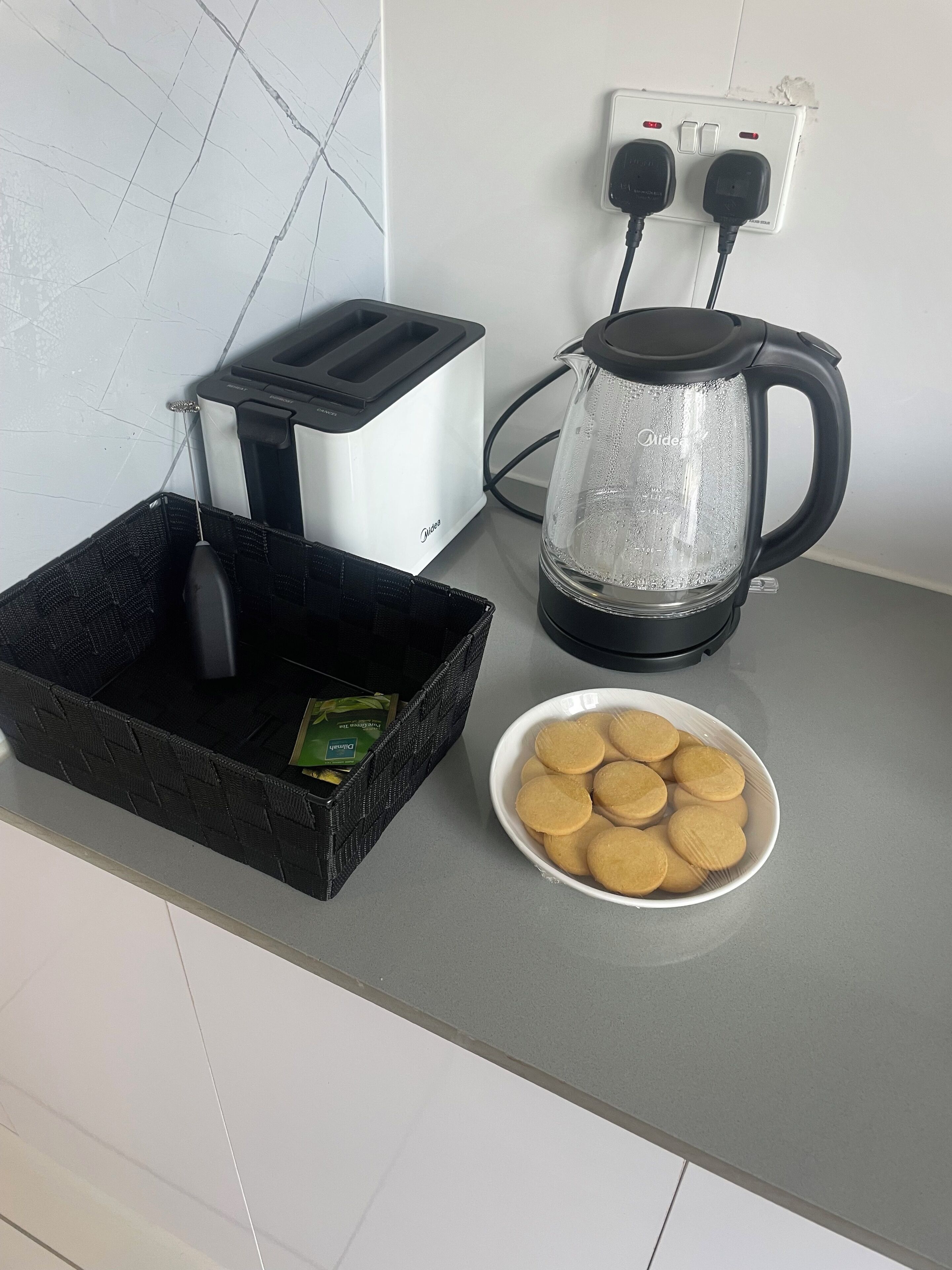 Eine Küchenarbeitsplatte mit einem Toaster, einer Kaffeemaschine, einem Korb mit einem Pfannenwender und einer Schüssel Kekse.