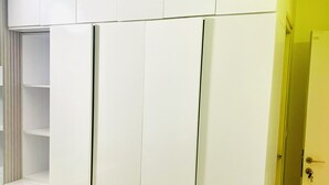 A room with a white wardrobe, a bench, and a door with a keyhole.