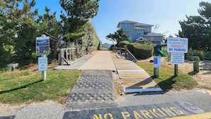 A private beach access area with a wooden walkway leading to a pool, surrounded by residential buildings and trees. - Daisy Duck - 5 BR Semi-Oceanfront Home in Schooner Ridge, Duck (Duck)
