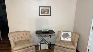 Two armchairs with a polka dot pattern, a small table with a framed picture, and a power outlet on the wall.