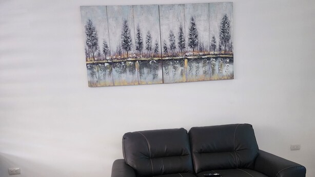 A black leather sofa in a room with white tiled flooring and a large painting of trees on the wall. - Adorable 3-bedroom house with AC in charming San Miguel (San Miguel)