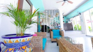 A sunlit indoor space with wicker furniture, a ceiling fan, and a reception area. - Modern Downtown Retreat | Comfortable and Convenient Stay in Cancun (Cancún)