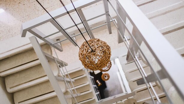 A modern interior with a hanging spherical wicker light fixture, white railings, and a reflective floor. - Modern Downtown Retreat | Comfortable and Convenient Stay in Cancun (Cancún)