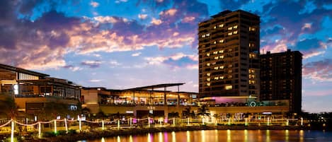 A hotel with multiple floors, a waterfront view, and outdoor seating areas with string lights.