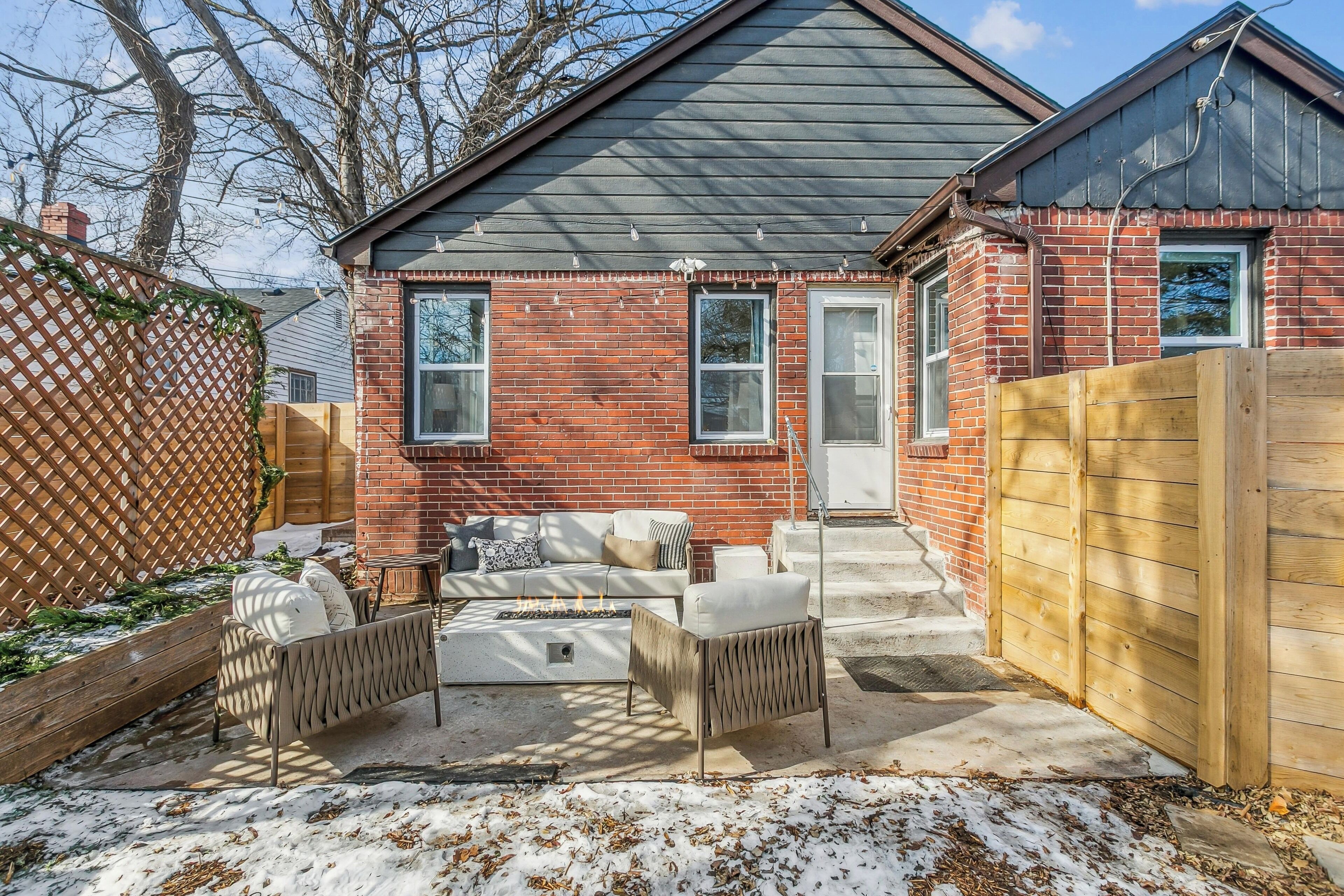 Une maison en briques dotée d’un patio aménagé avec des meubles d’extérieur et un foyer.