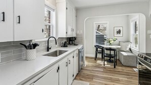 Una cucina moderna con mobili bianchi, un lavello doppio e un'area pranzo con tavolo e sedie.