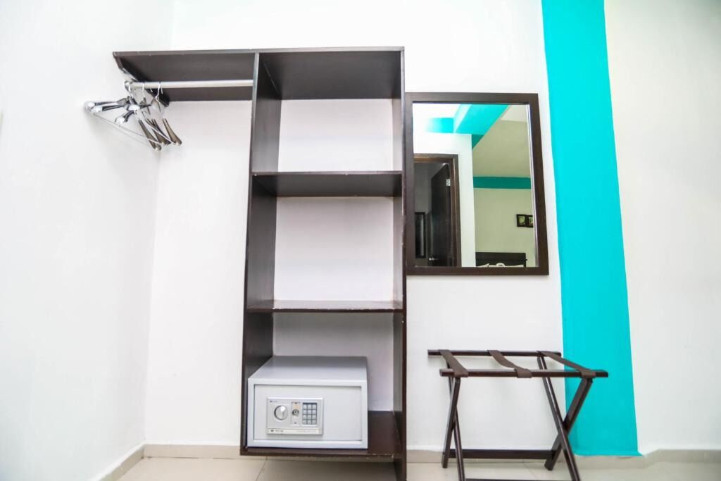 Ein Zimmer mit weißer Wand, einer Akzentwand in Türkis, einer eingebauten Schrankwand mit Radio und einem kleinen Tisch.