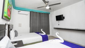 Habitación de hotel con dos camas, ventilador de techo, televisión y un cuadro en la pared.