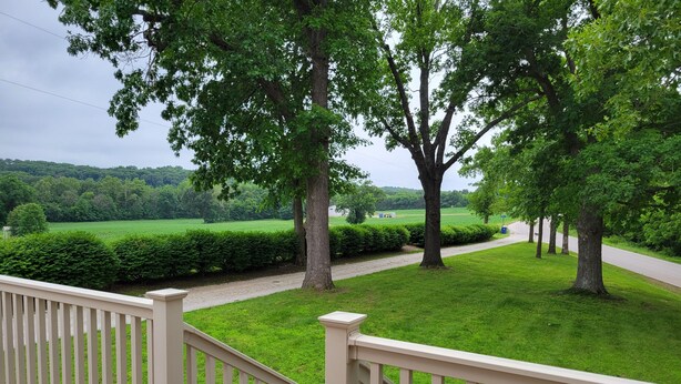 A deck with a white railing overlooking a well-maintained lawn and trees. - Shepherd Homestead on 20+ Acres, Close to Everything (Union)