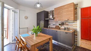 A modern kitchen with a wooden table, a sink, and cabinets. There is a clock on the wall and a plant on the table. - Cozy apartment in Savona with WiFi (Savona)