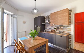 A modern kitchen with a wooden table, a sink, and cabinets. There is a clock on the wall and a plant on the table. - Cozy apartment in Savona with WiFi (Savona)