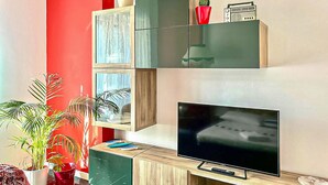 A living room with a flat-screen TV, wooden cabinets, and a red accent wall. - Cozy apartment in Savona with WiFi (Savona)