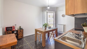 A compact kitchen with a wooden table, a sink, and a microwave. There's a potted plant on the table and a clock on the wall. - Cozy apartment in Savona with WiFi (Savona)