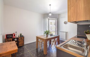 A compact kitchen with a wooden table, a sink, and a microwave. There's a potted plant on the table and a clock on the wall. - Cozy apartment in Savona with WiFi (Savona)