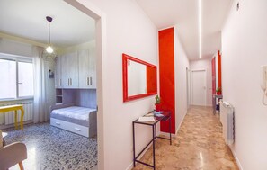 A narrow hallway with a bed, a desk, and a mirror. - Cozy apartment in Savona with WiFi (Savona)